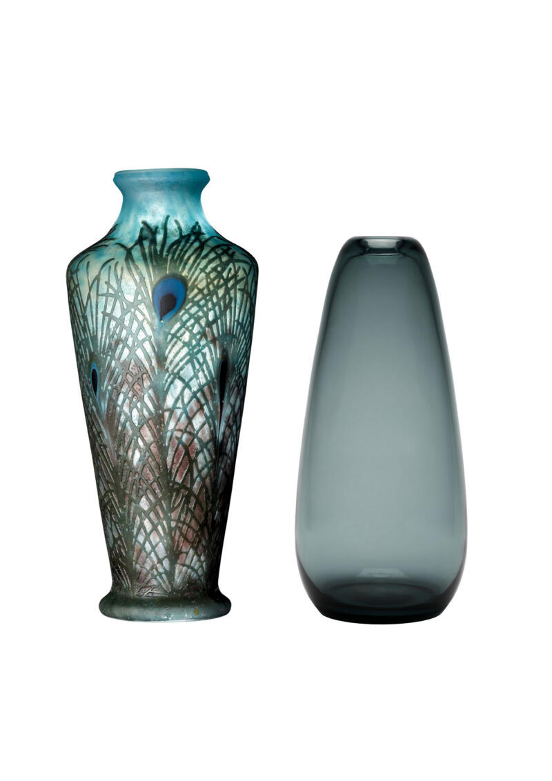 2 Glasvasen: die linke Jugendstilvase zeigt ein feines Muster aus olivfarbenen Federn auf hellblauem Grund, die rechte Vase aus dem 20. Jahrhundert ist aus graublauem Glas und setzt auf eine glatte Oberfläche.
