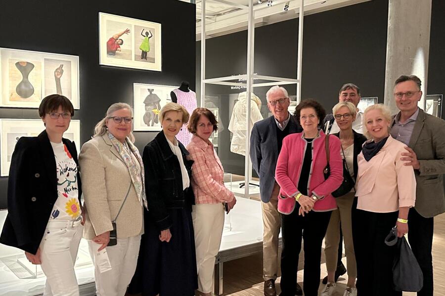 Zehn Menschen stehen in einem Ausstellungsraum und schauen in die Kamera.