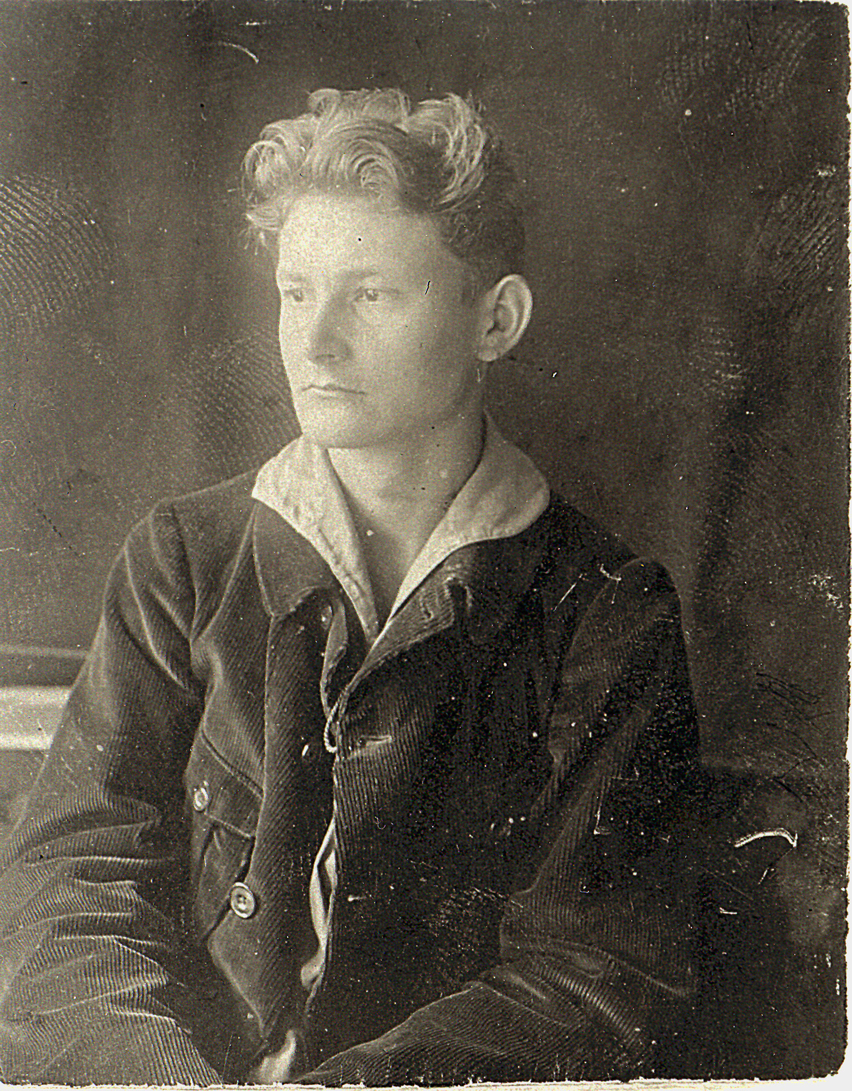 schwarz weiß Foto eines jungen Mannes mit dunklem Kordanzug und ernstem Gesichtsausdruck