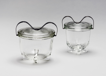 zwei Gefäße aus durchsichtigem Pressglas mit einem Metallbügel auf der Oberseite