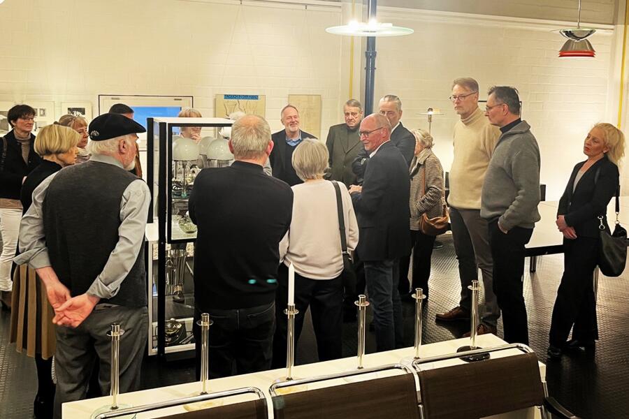 Besucherinnen haben sich um eine Vitrine versammelt und schauen interessiert auf eine Leuchte.
