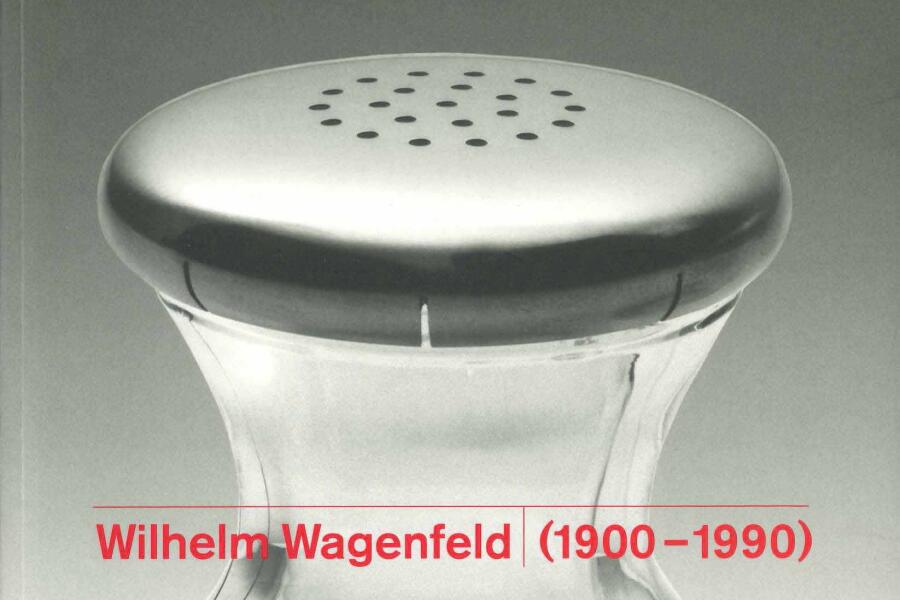 Rote Schrift über einer Nachaufnahme eines Salzstreuer aus transparentem Glas mit einem Deckel aus Edelstahl. Der Steuer hat eine außergewöhnliche Form mit einer Taillierung in der Mitte.