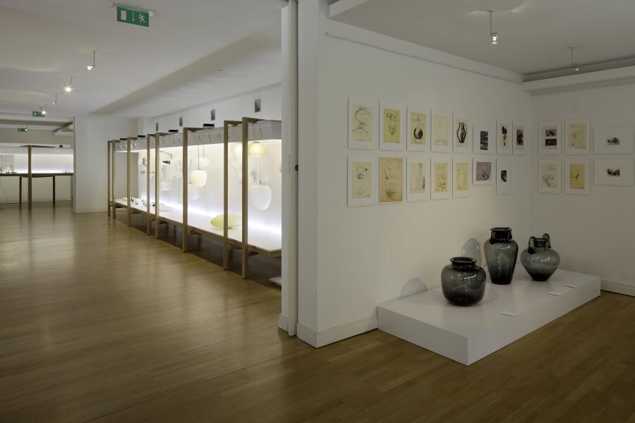 links: eine lange Vitrine mit Leuchten-Entwürfen von Wilhelm Wagenfeld, rechts: Bodenvasen und auf die Wand gehängte Entwurfszeichnungen